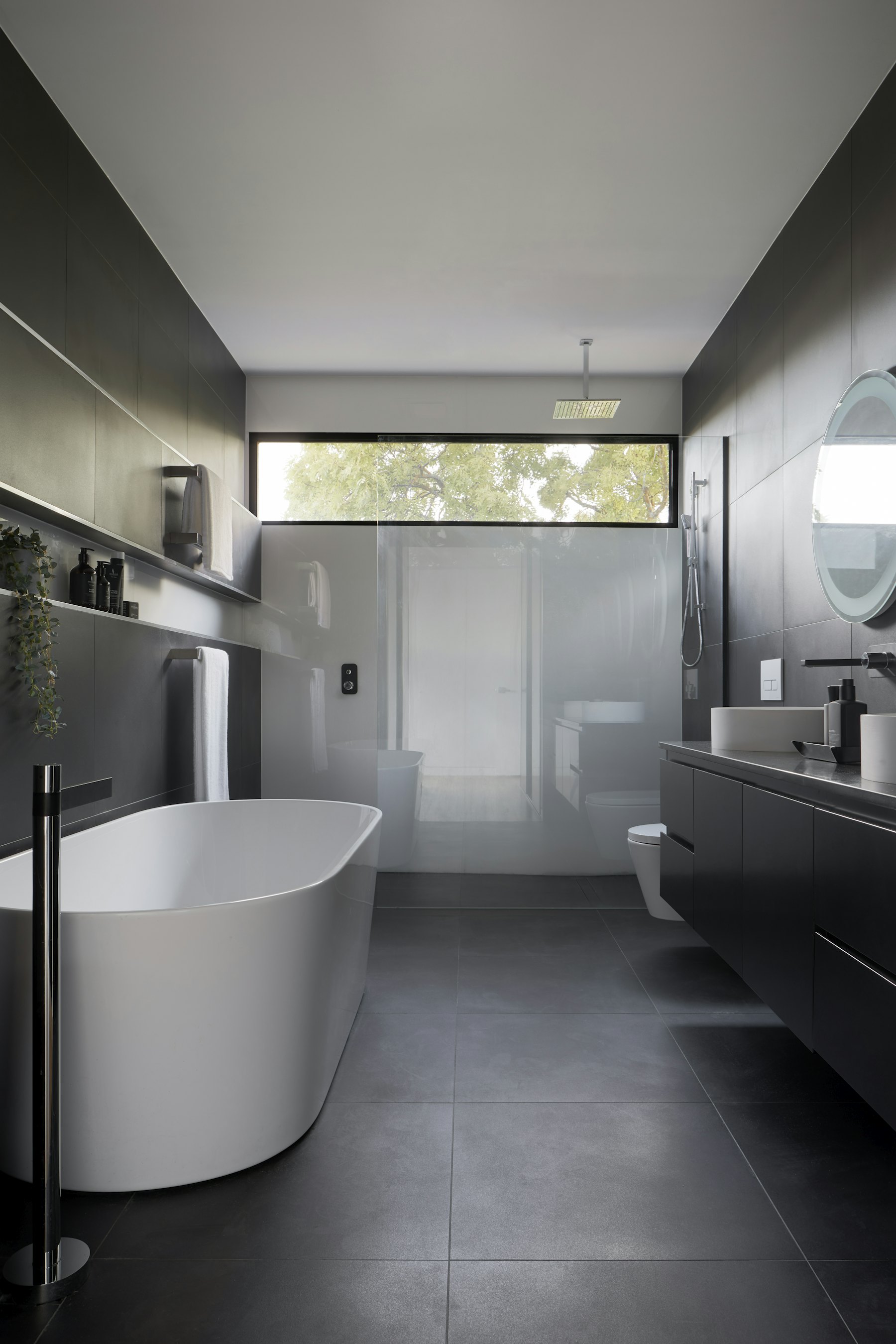 Dark stone family bathroom with freestanding bath and black brassware