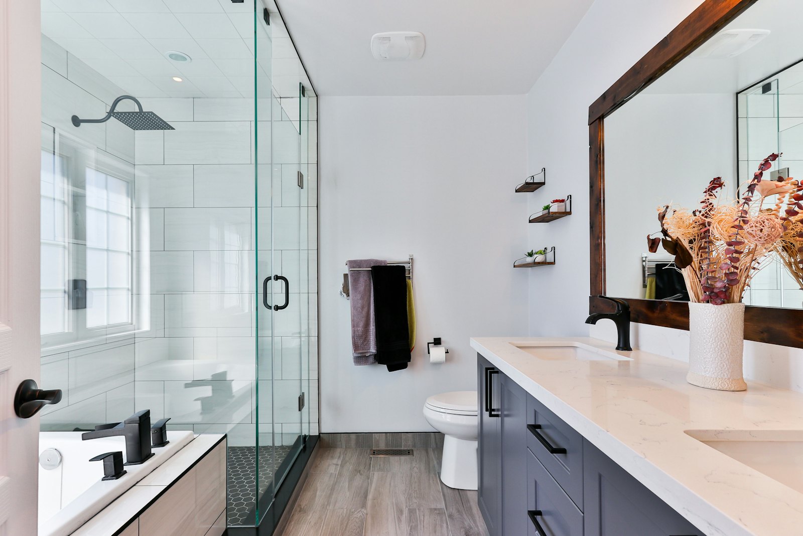 Glass & Light — Frameless walk-in screen, linear drain and a warm walnut vanity.