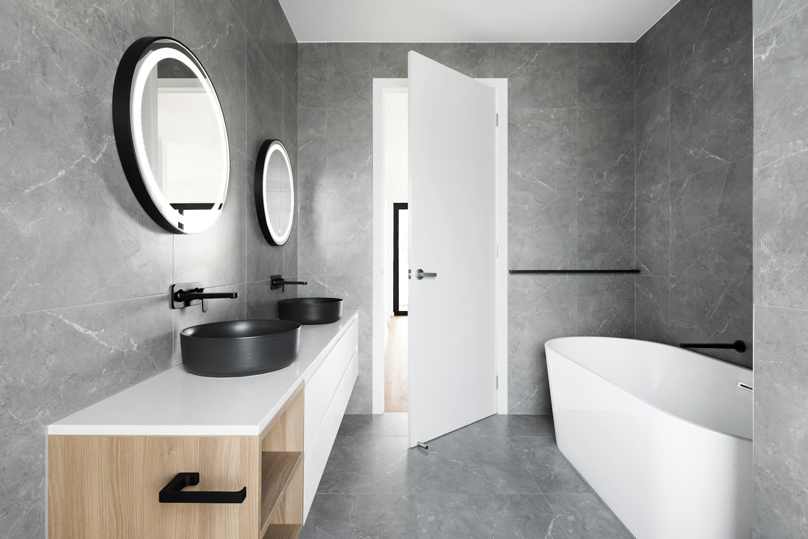 Grey stone-effect wet room with round mirror and freestanding bath