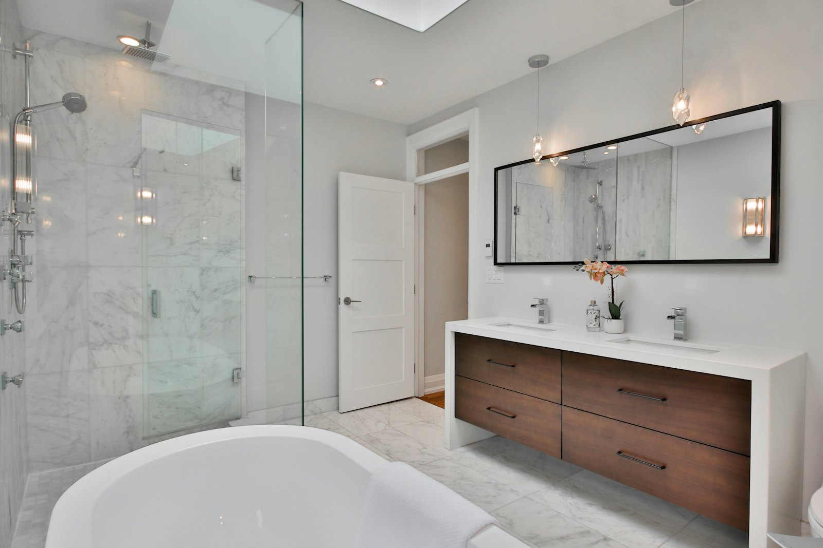 Marble-tiled ensuite with frameless walk-in shower and floating walnut vanity
