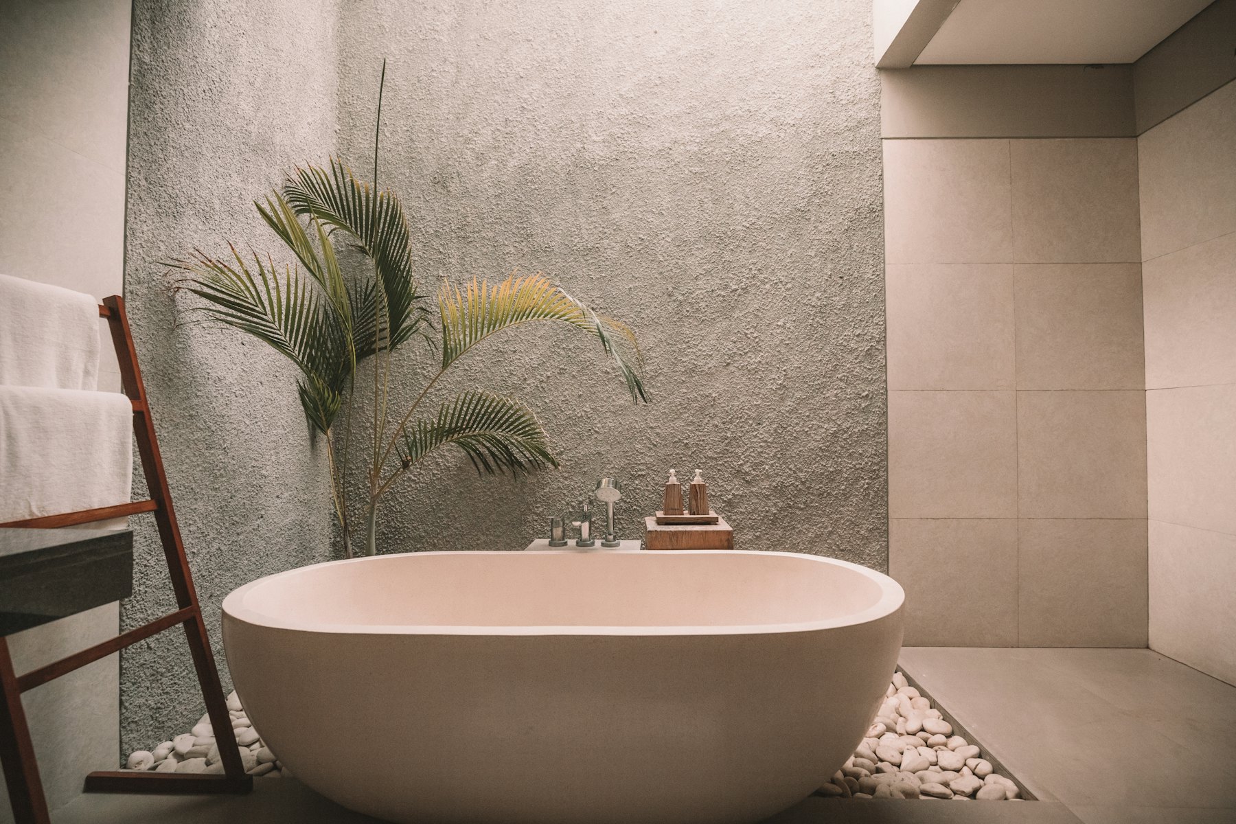Plaster & Blush — Lime-plaster finish, pebble floor inlay and a blush freestanding bath.